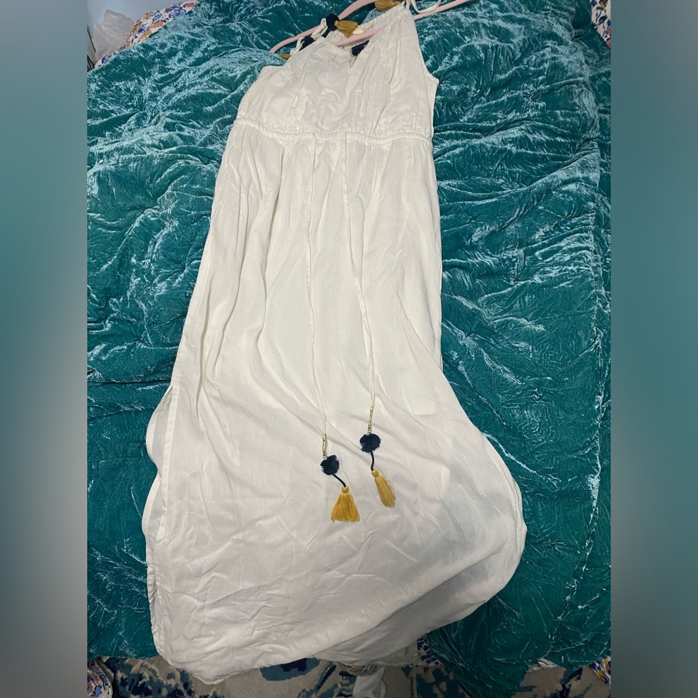 Long white dress with blue and gold tassels.